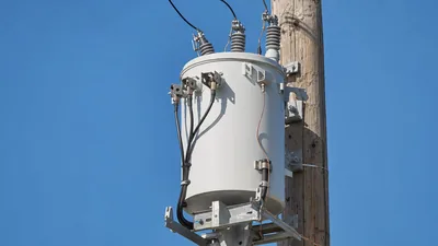 Overhead single-phase power pole transformer mounted on a utility pole with primary bushings and surge arresters